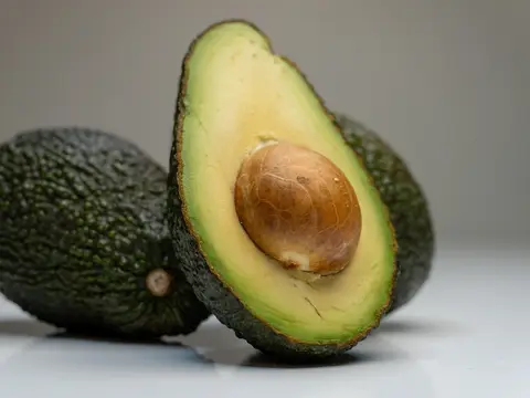 Un aguacate entero y otro partido por la mitad con su hueso