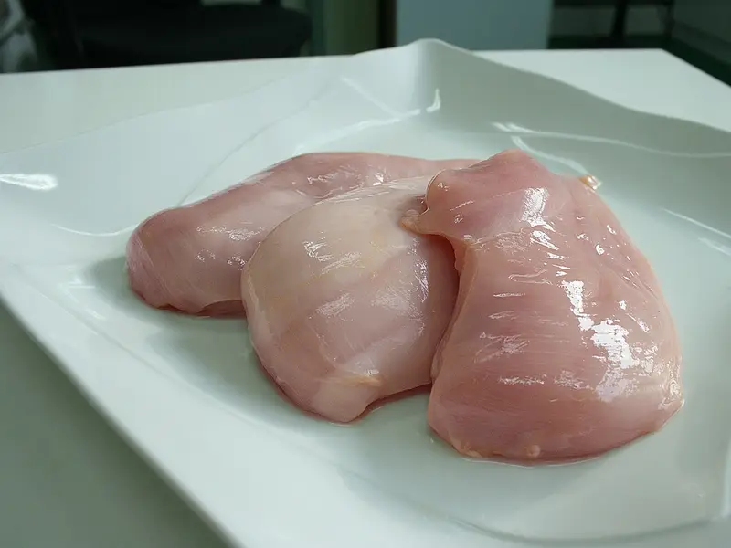 Dos pechugas de pollo crudas sobre un plato blanco