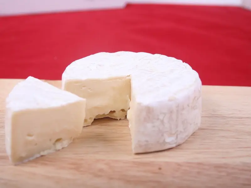 Queso brie entero con una cuña cortada